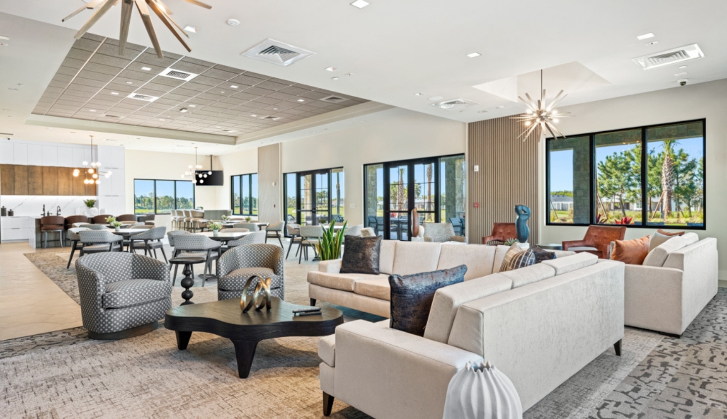 The gathering lounge inside The Resort Club at Esplanade, sofas and tables beneath tall windows